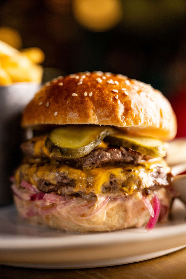 Juicy beef burger with cheese, gherkin & pink onions in a seeded bun